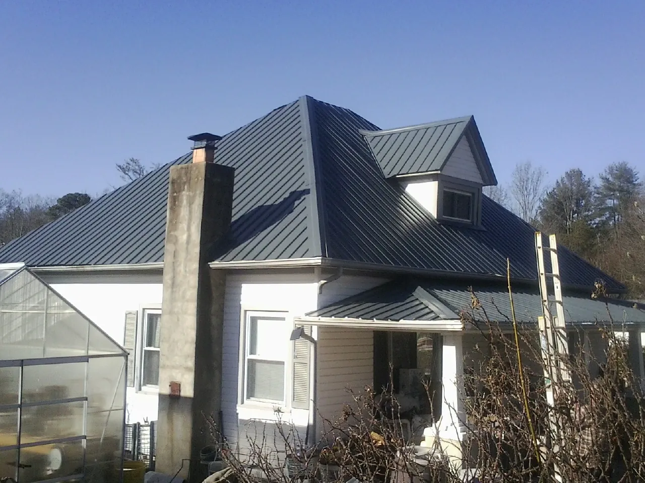 Dark blue standing seam metal roof on a white farmhouse with dormer — Slate & Tile Roof Repair by Roofing Brothers in Cheshire