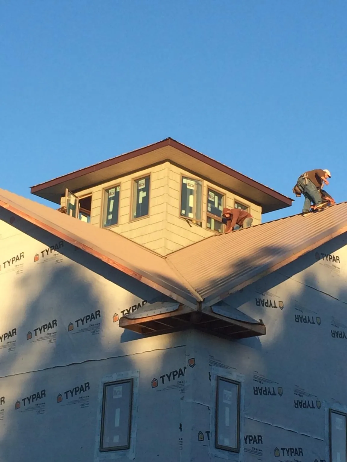 Roofers working around a rooftop cupola on a new metal roof at sunset — Roof Waterproofing in Cheshire by Roofing Brothers